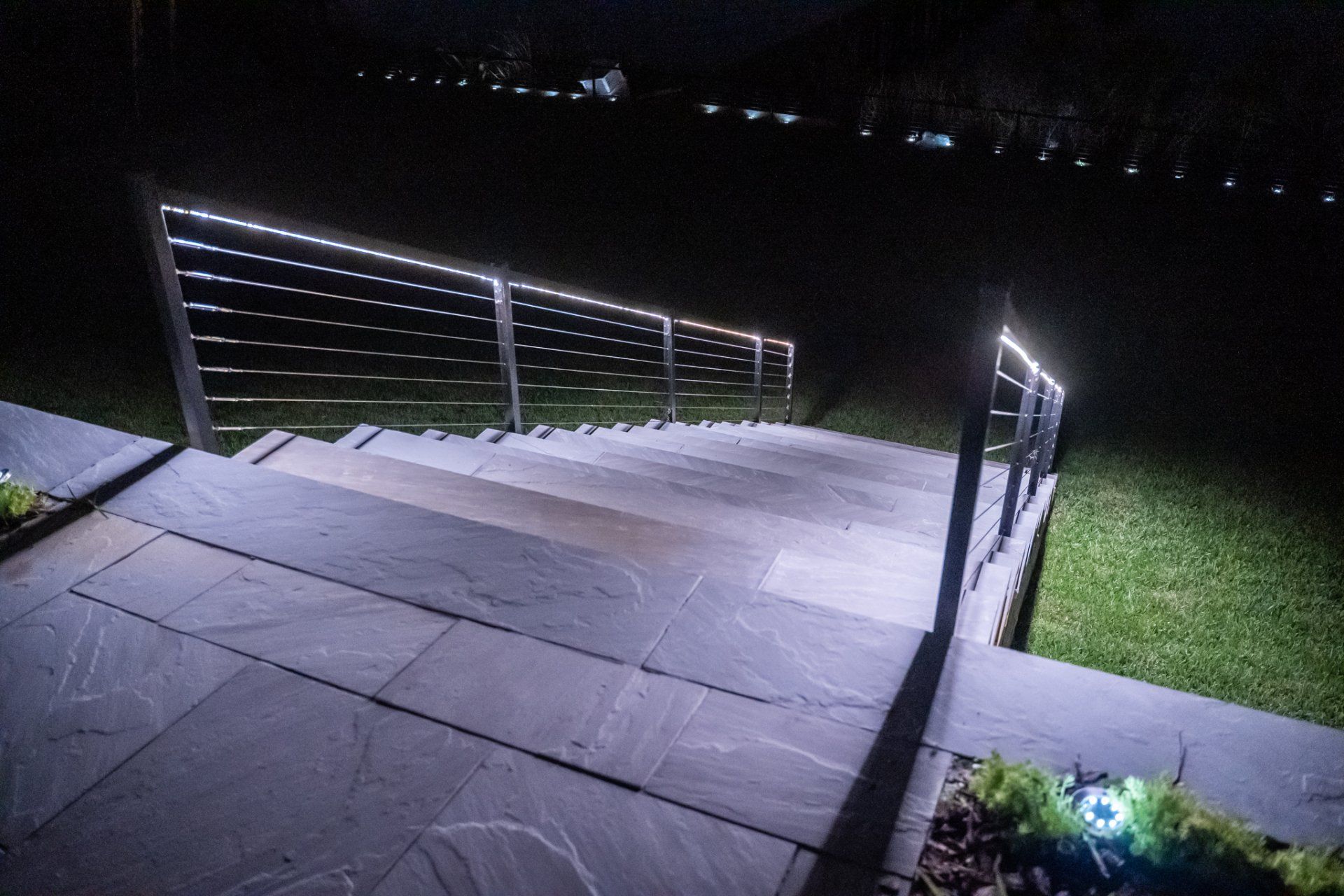 Outdoor stairway with illuminated railing at night.
