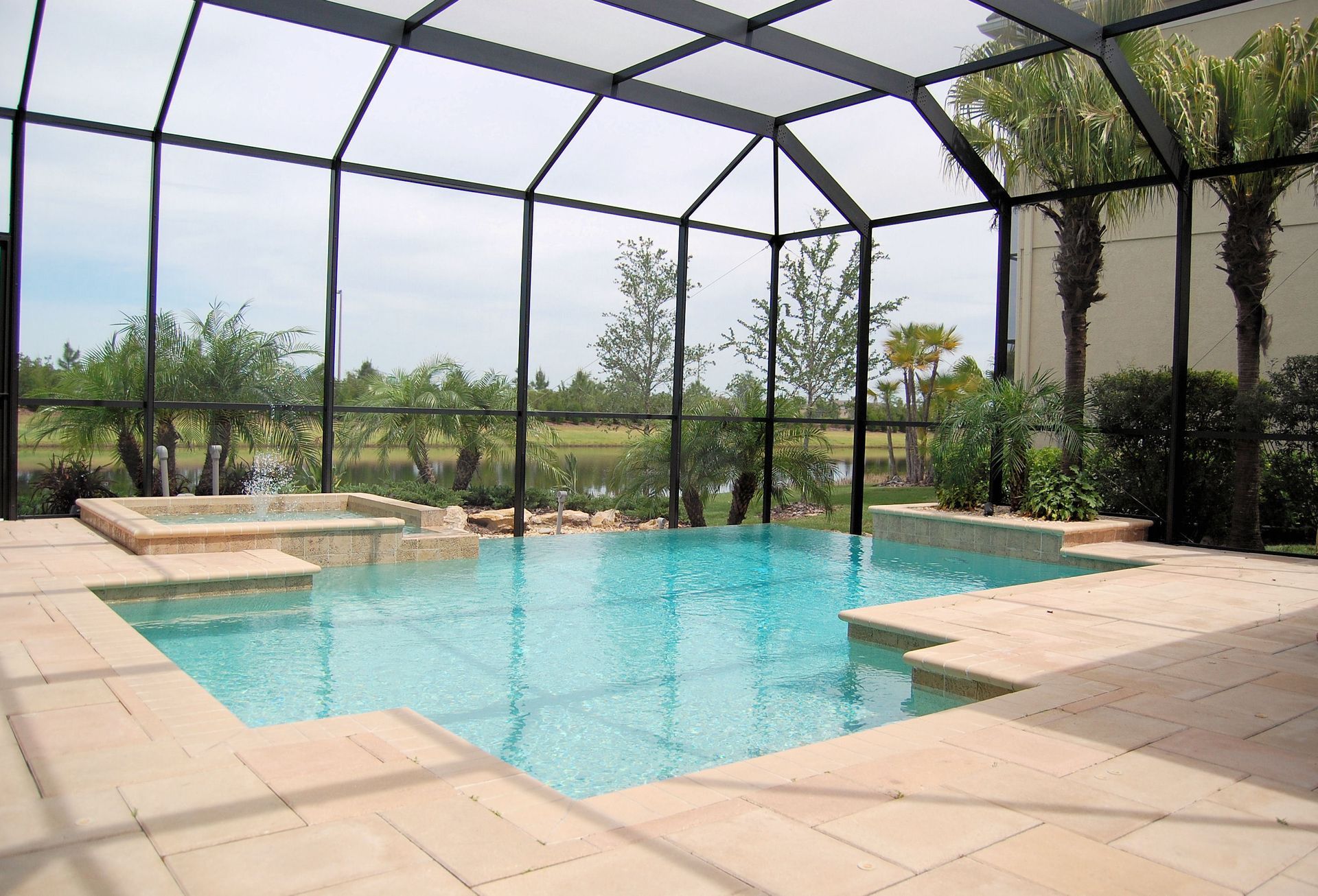 Pool enclosure with a pool, spa, and tile patio. Black framed screen surrounds pool.